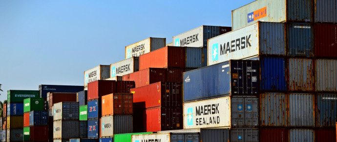 Stacked Maersk shipping containers at a port terminal