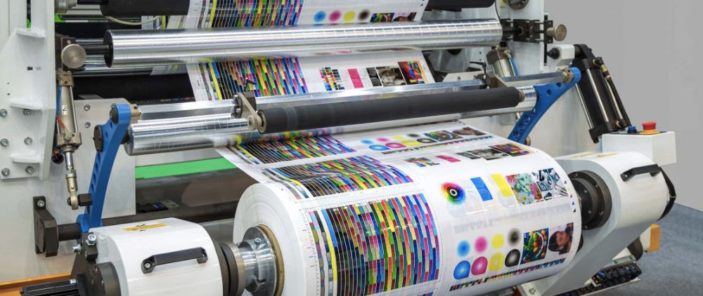 A wide-format printing press running a colour-printed sheet