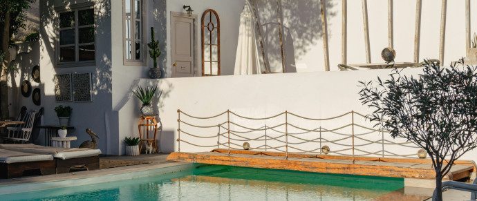 A whitewashed Cycladic courtyard with a swimming pool and olive tree