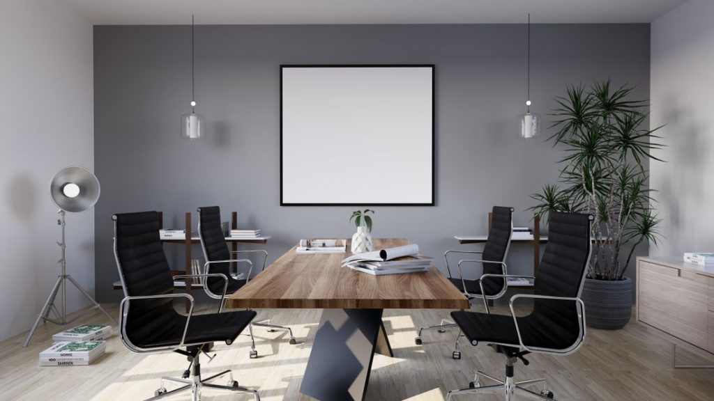 An empty boardroom with a single long wooden table and chairs set around it