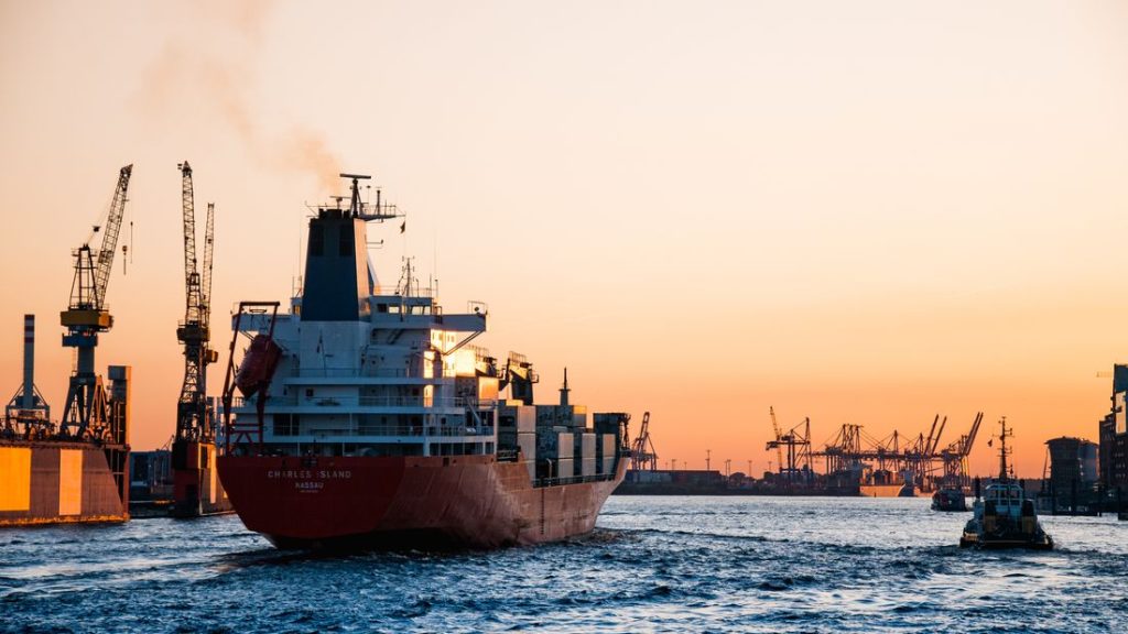 Cargo ships and harbour cranes silhouetted against a sunset at a European port