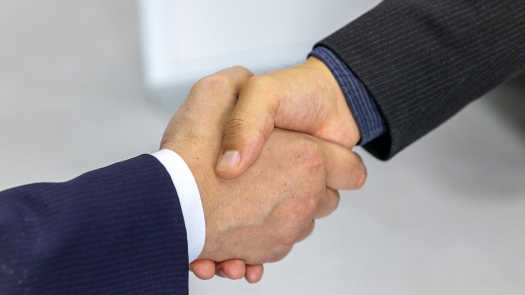 Two people in business attire shaking hands at the close of a meeting