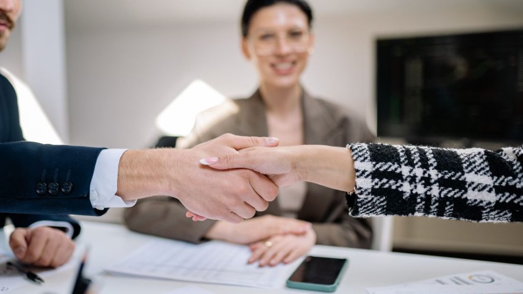 A handshake sealing an agreement while colleagues look on across the table